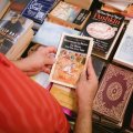 Woman holding old book with other books in background at Book Fair.